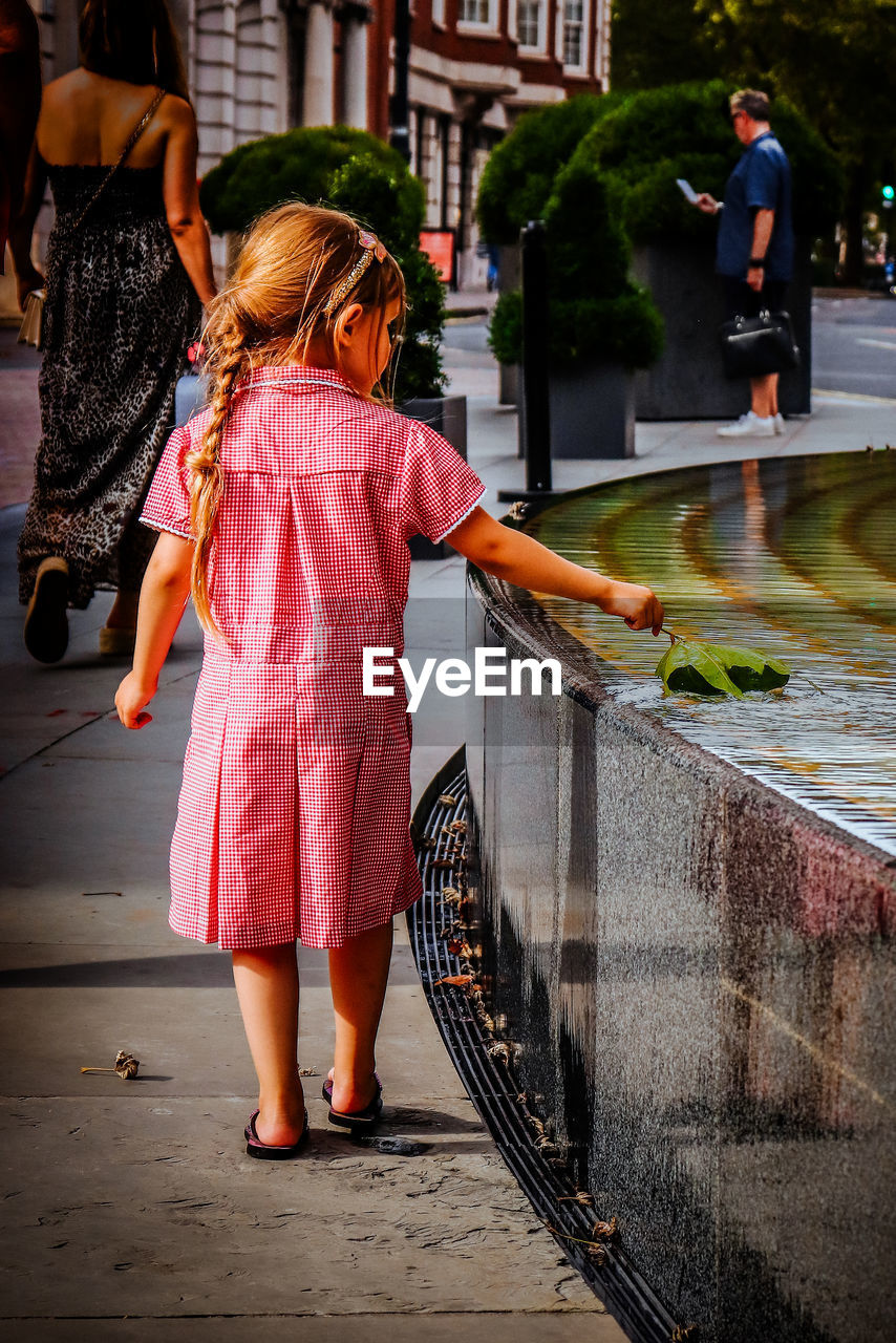 rear view of young woman standing against railing