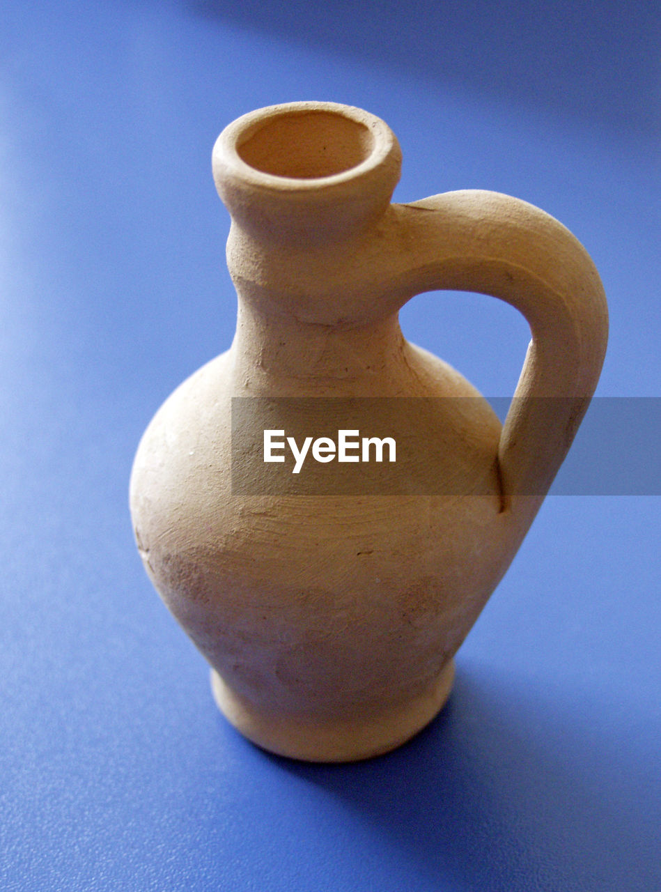 Close-up of vase over blue background
