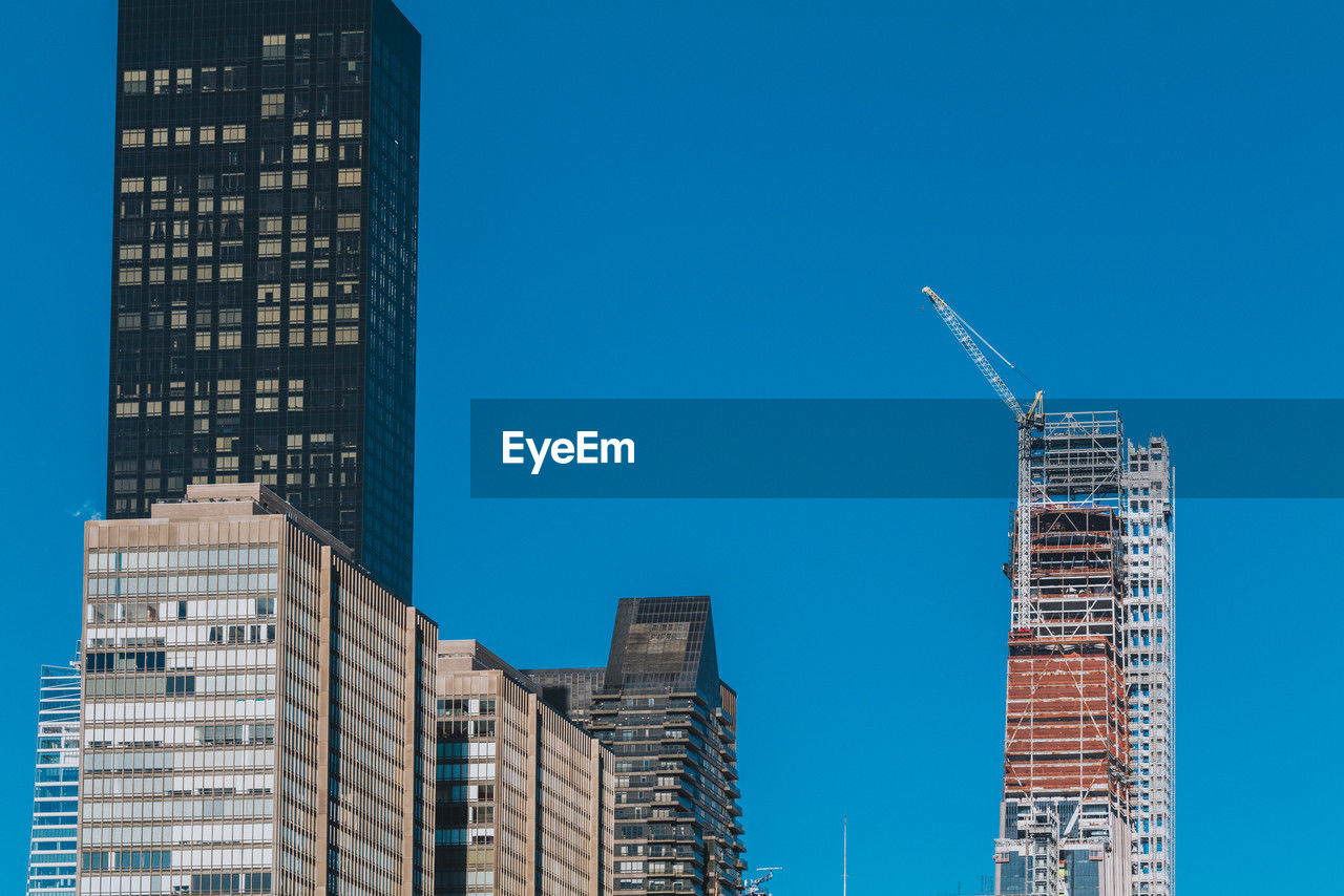 Building under construction with crane on a building in new york city on a blue sky background