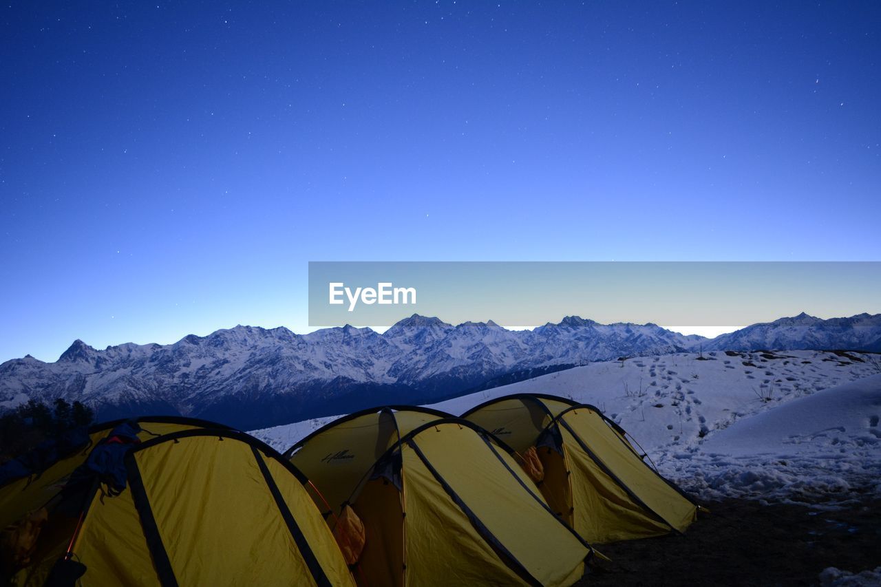 TENT ON MOUNTAIN AGAINST BLUE SKY