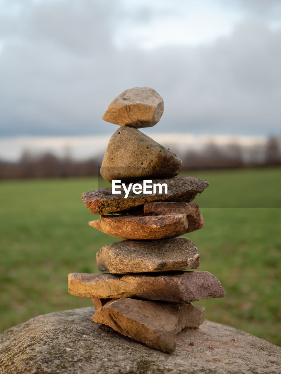 Stack of stones on field against sky