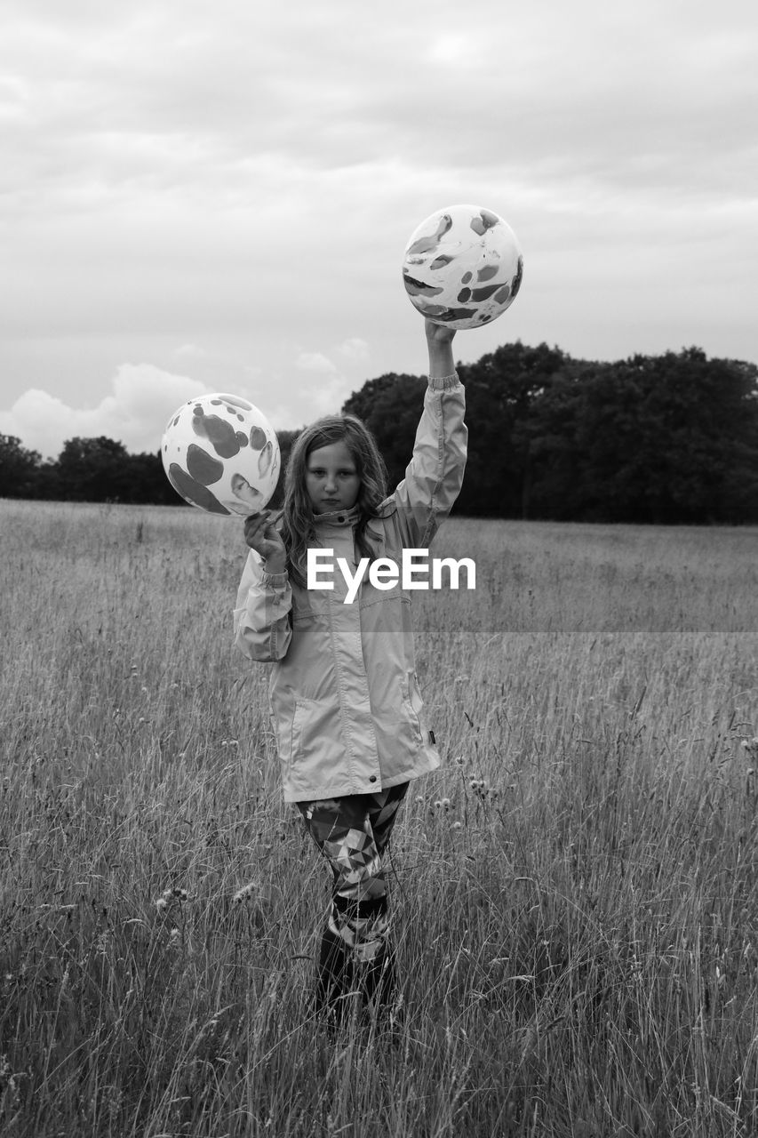 GIRL STANDING ON FIELD AGAINST SKY