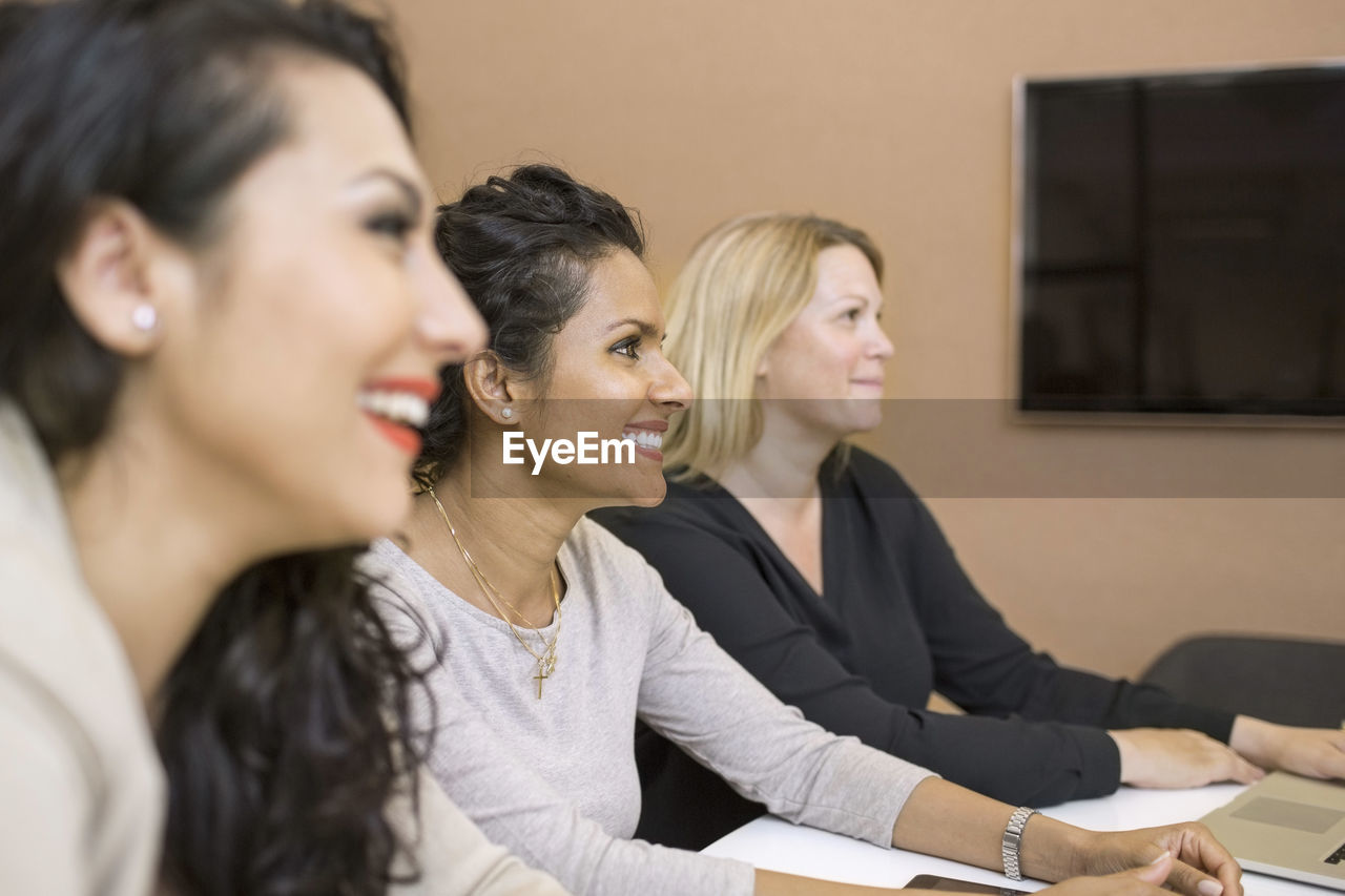 Side view of businesswomen sitting in meeting at creative office
