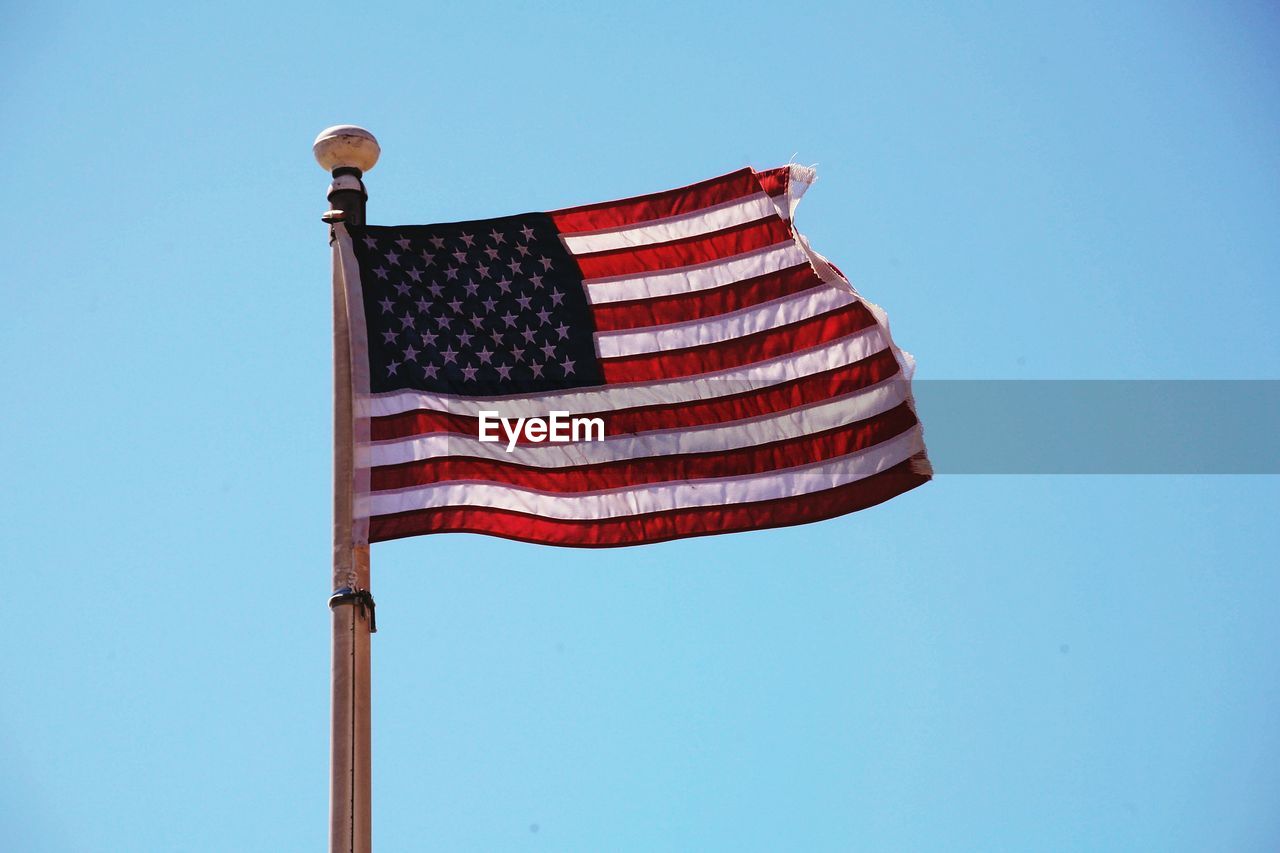 Low angle view of american flag against blue sky