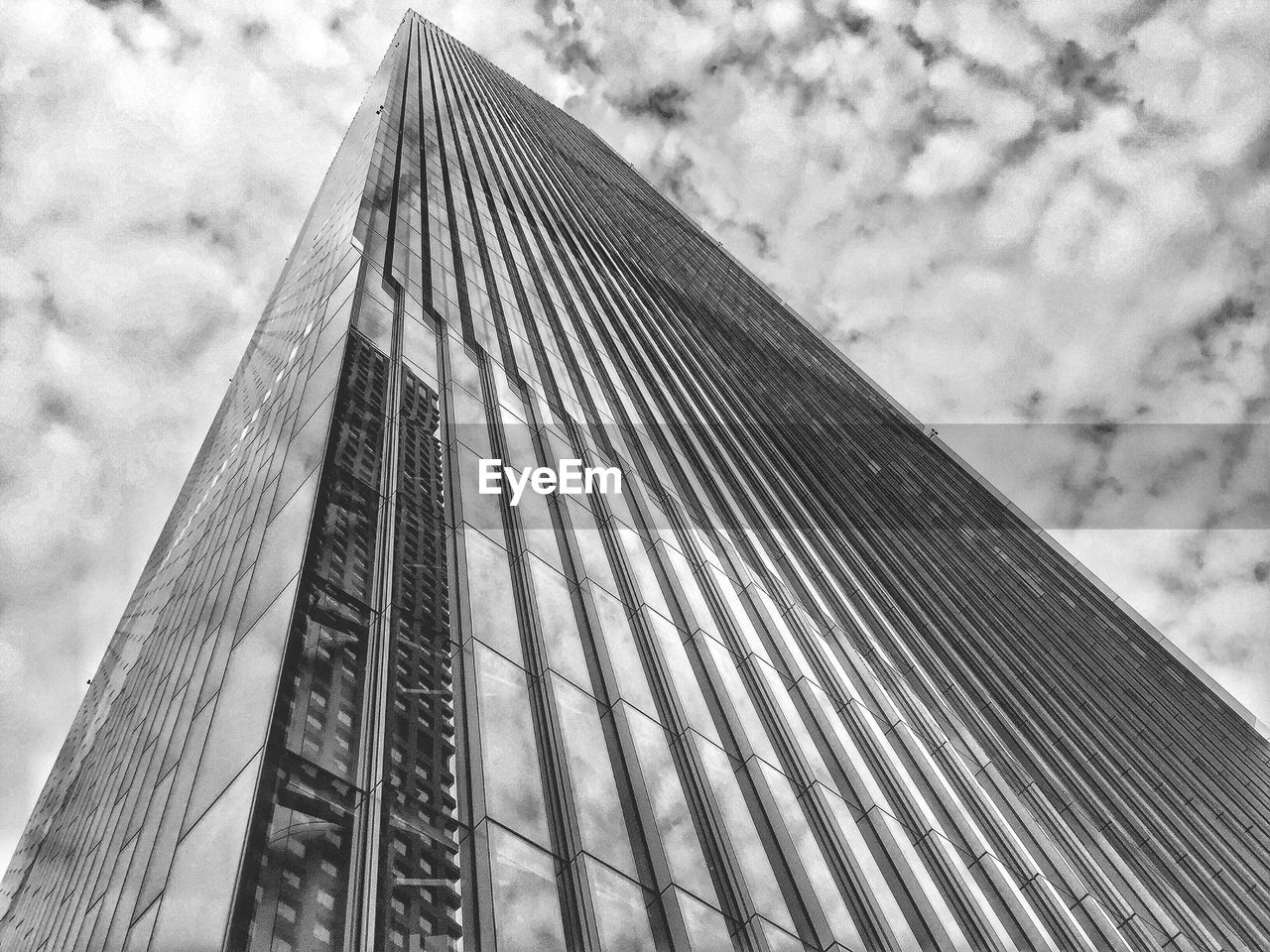 LOW ANGLE VIEW OF MODERN SKYSCRAPER AGAINST CLOUDY SKY