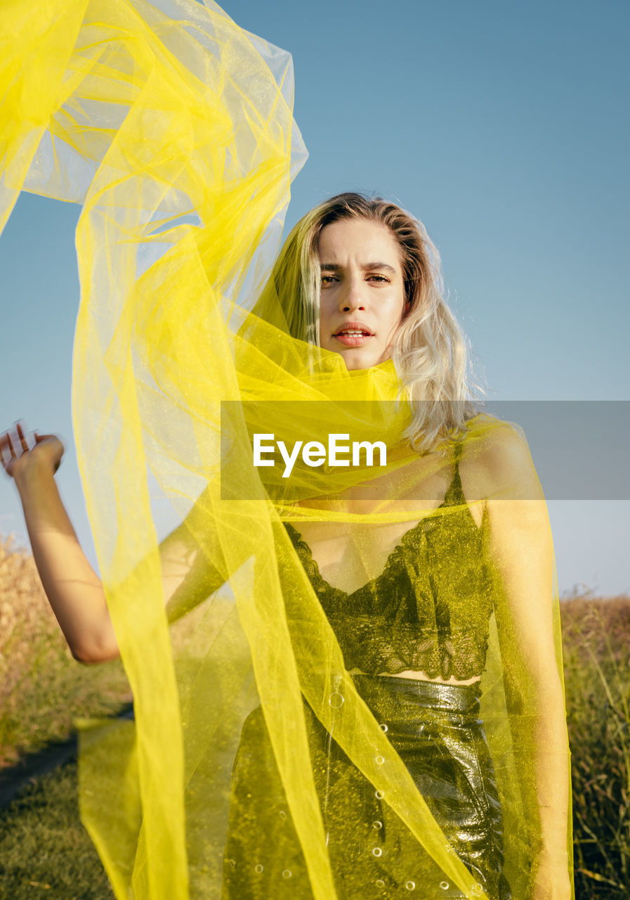 Portrait of woman holding netting while standing against plants