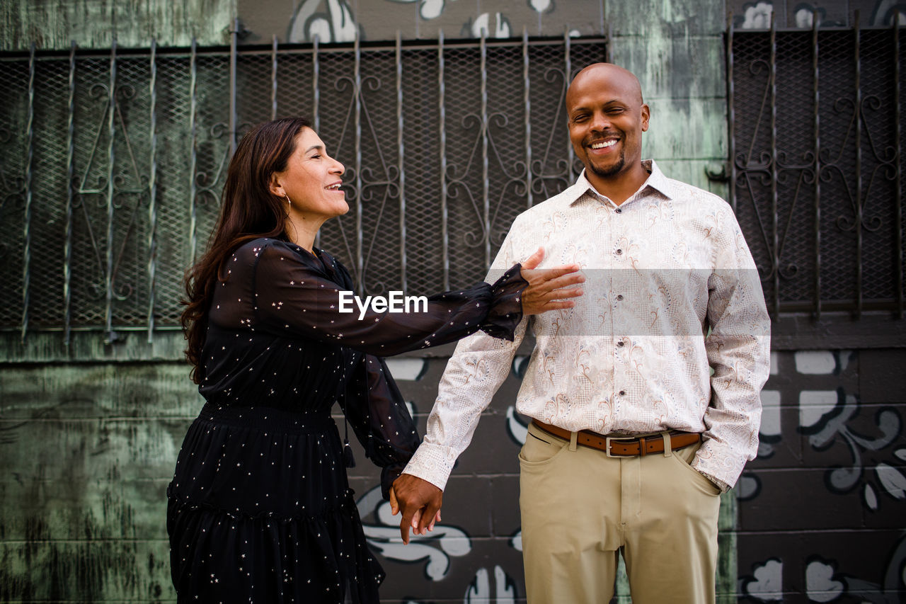 Late forties couple standing in front of mural in san diego