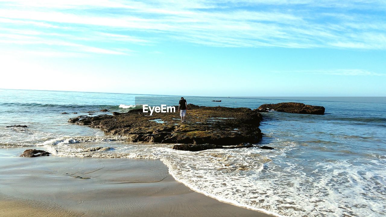 Man standing on rock formation amidst sea