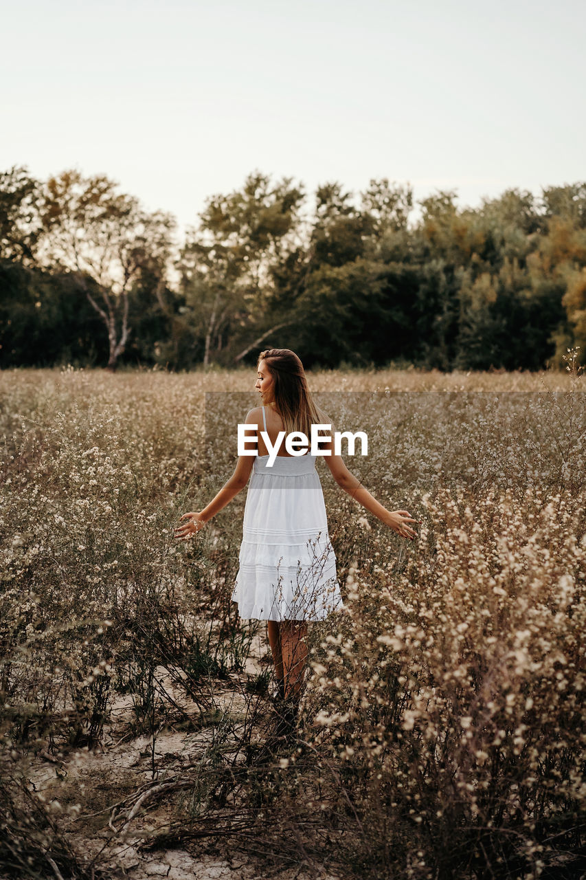 Tender lady standing in blooming field