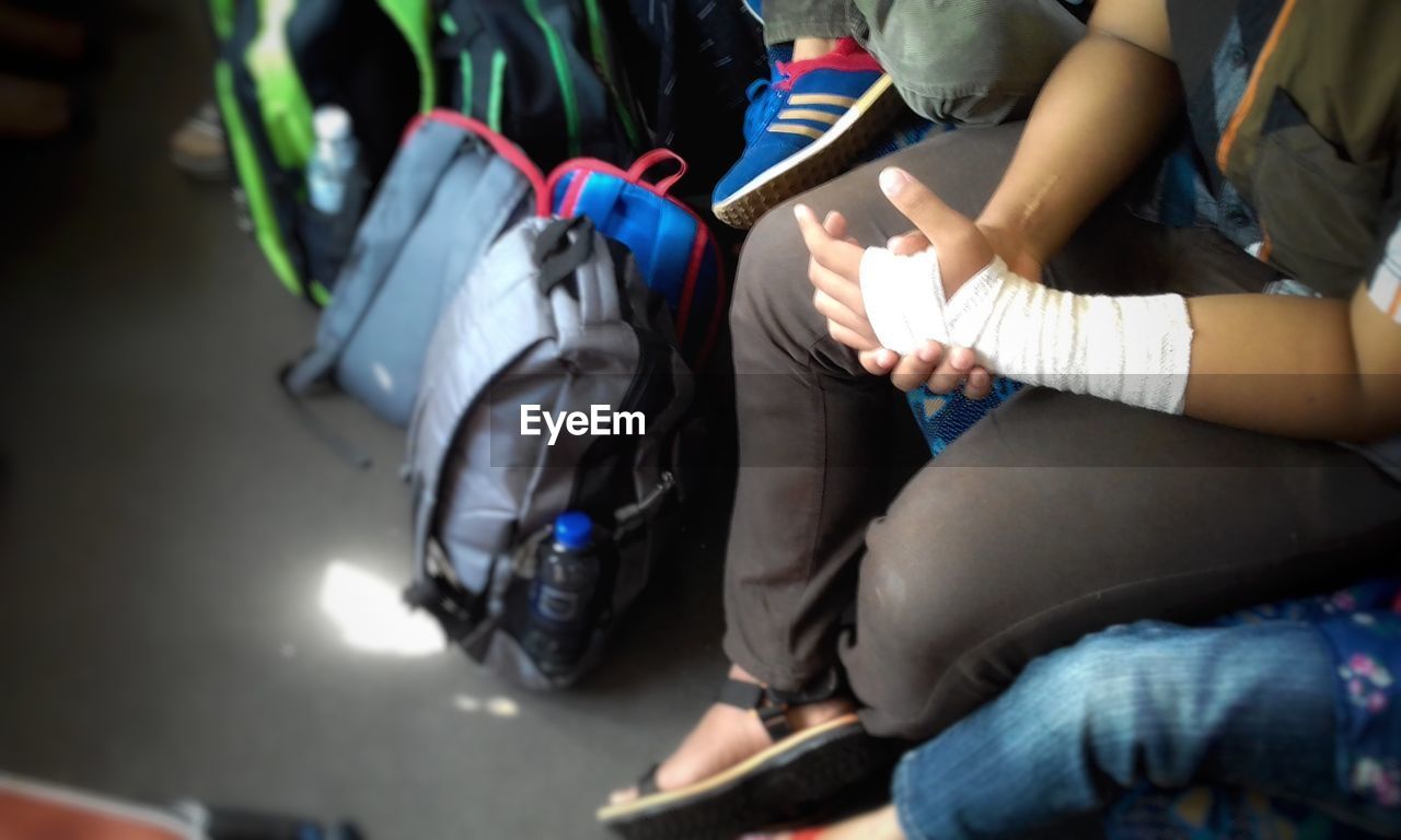 Low section of man with bandage sitting indoors