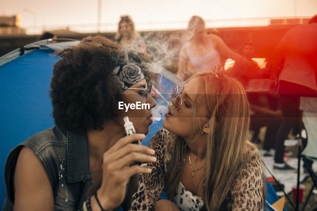 Couple smoking together outside tent at musical event