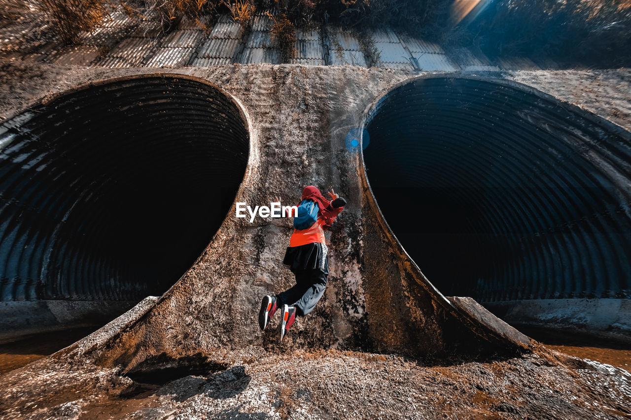 Rear view of teenage girl jumping at dam