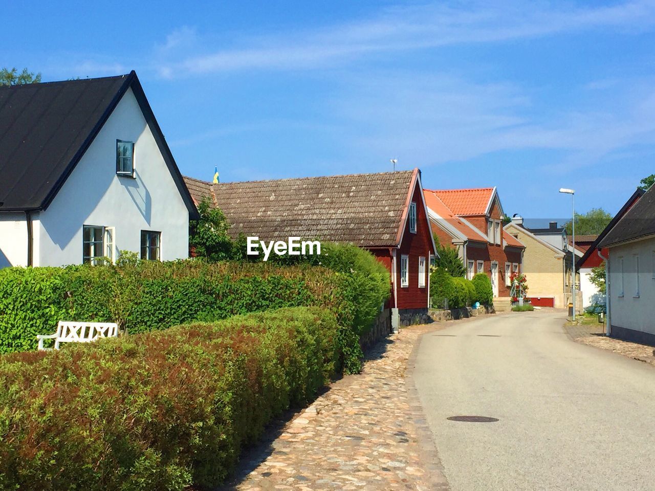 Road amidst houses in village against sky