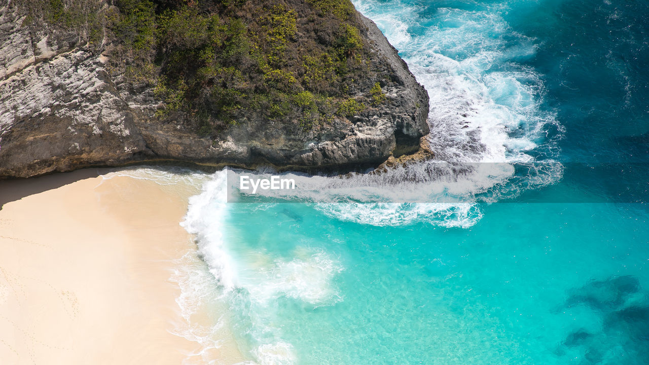 HIGH ANGLE VIEW OF WAVES BREAKING ON ROCK