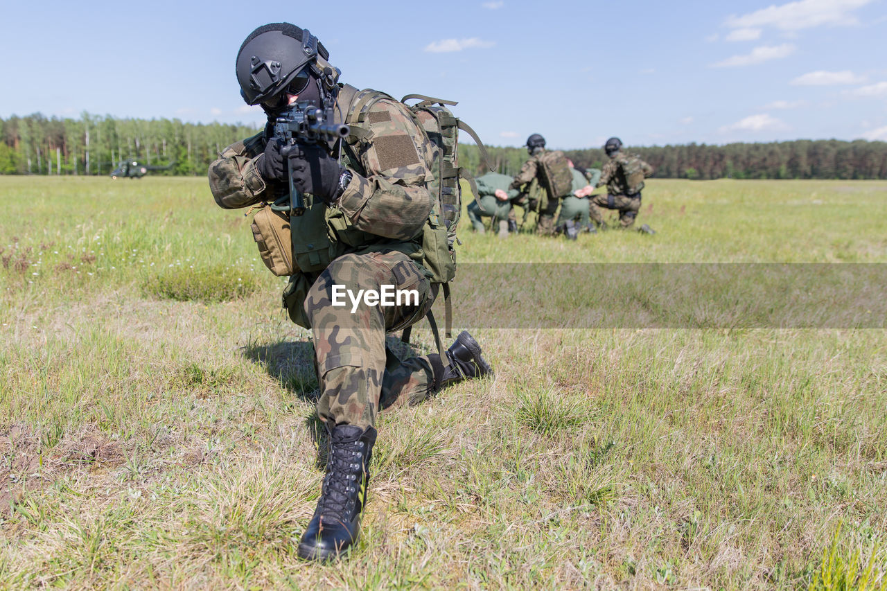 Soldier with gun on field while colleagues