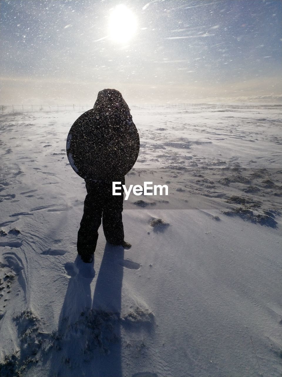 Girl standing on snow covered field against sky