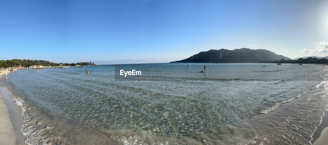 water, sea, land, sky, beach, shore, body of water, scenics - nature, ocean, beauty in nature, nature, coast, wave, sand, travel destinations, tranquility, travel, tranquil scene, landscape, blue, coastline, environment, holiday, vacation, horizon, trip, day, tourism, clear sky, bay, outdoors, no people, mountain, sunny, sunlight, panoramic, idyllic, cloud, island, motion, seascape, wind wave, summer, non-urban scene, bay of water, sports, water's edge, lagoon