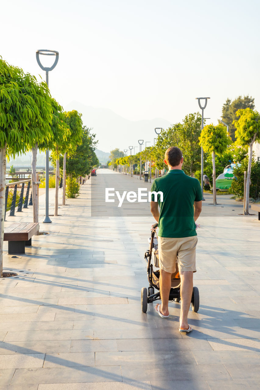 Rear view of man riding bicycle on footpath