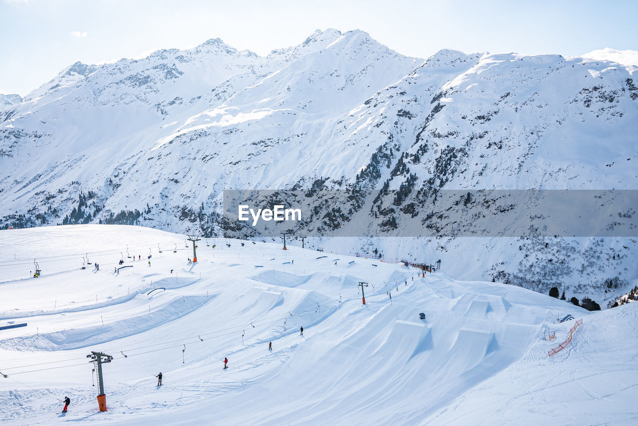 View of tourists enjoying winter sport on snow covered alps