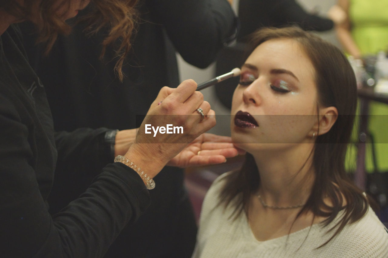 Beautician applying make-up to woman