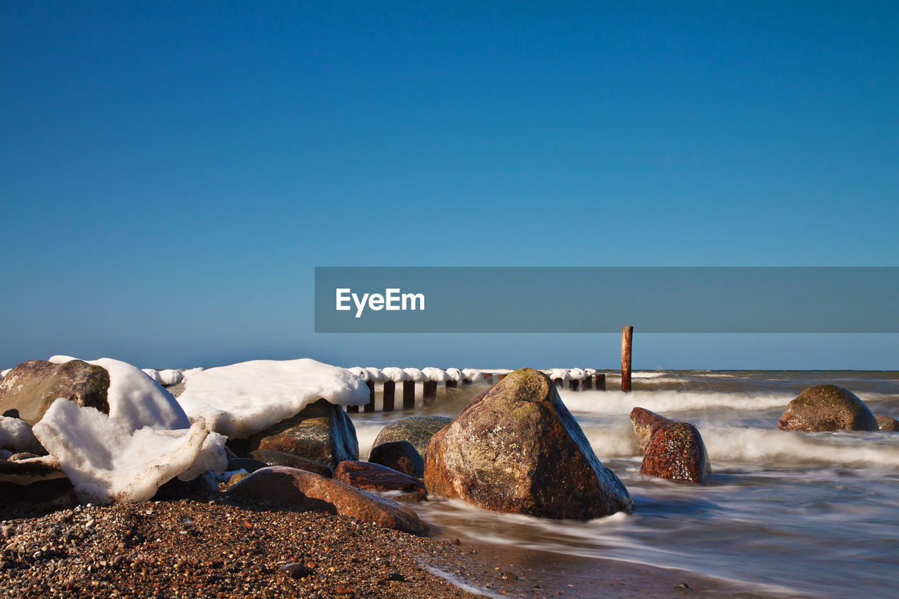 Scenic view of beach against clear blue sky