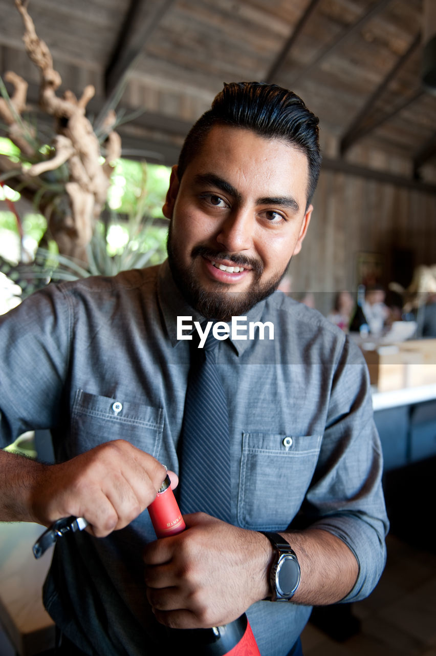 Portrait of bartender opening wine bottle