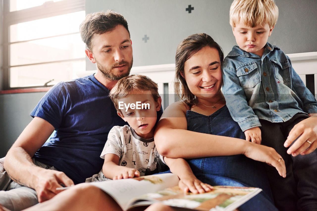 Parents and kids sitting on bed at home