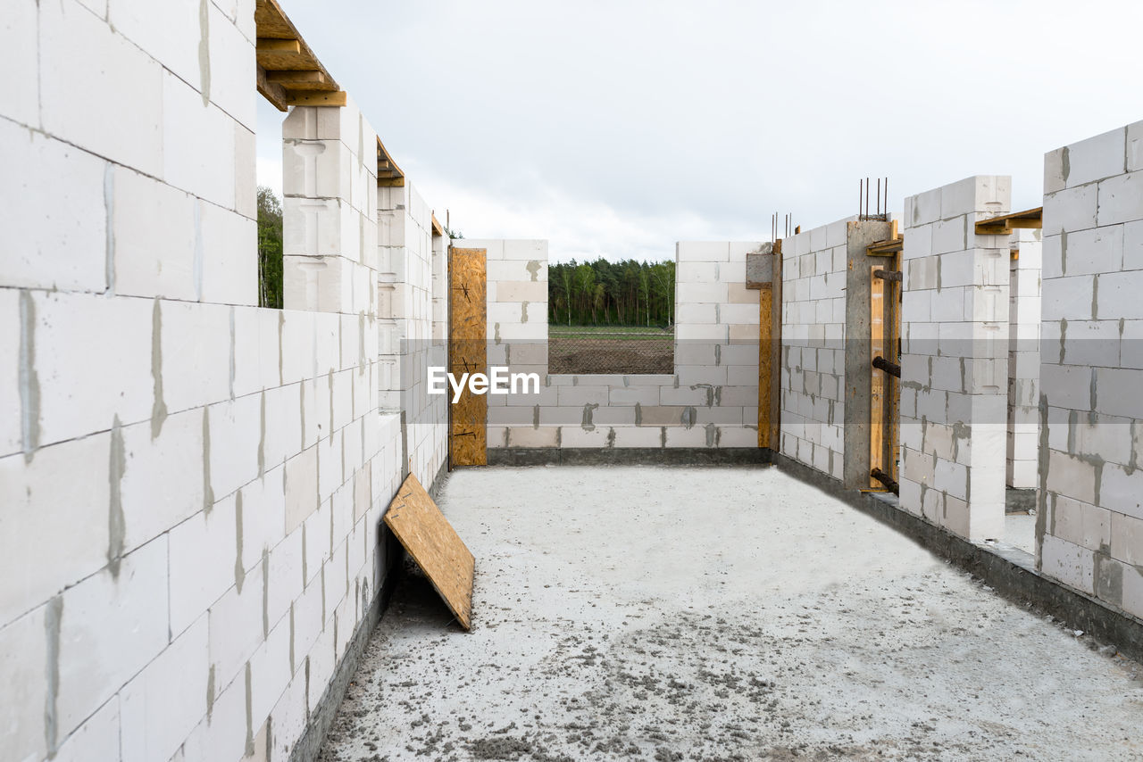 The walls of a house built of white brick with reinforced concrete pillars at the end