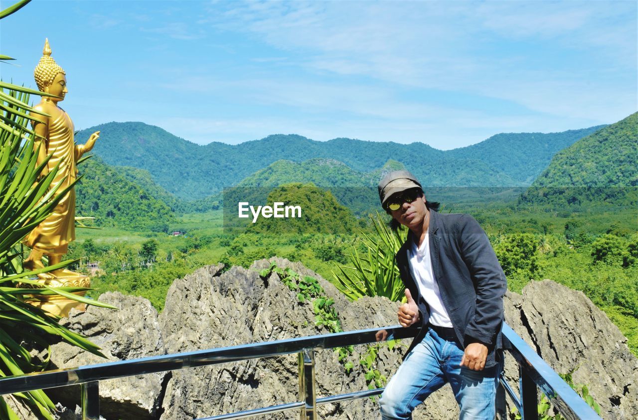 Mature man wearing sunglasses standing against landscape during sunny day