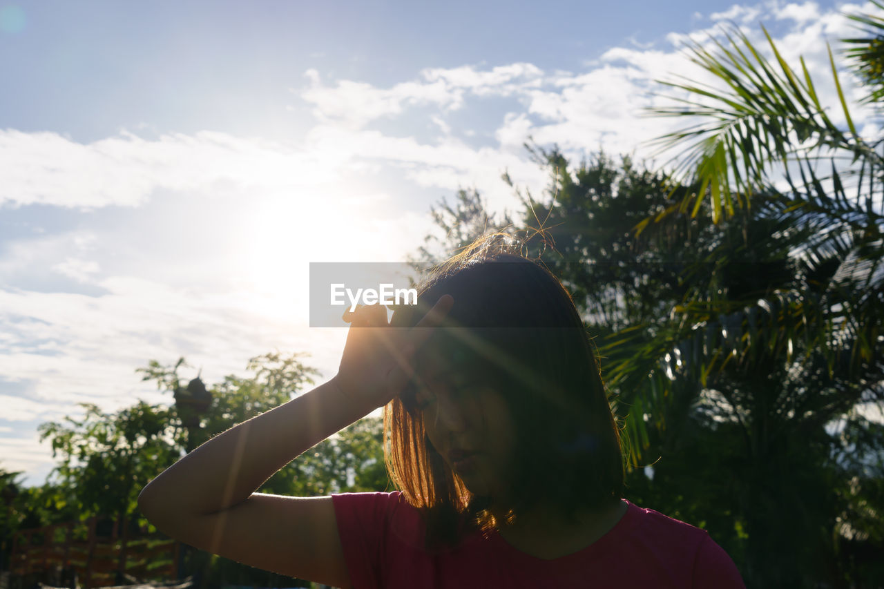 Young woman against trees