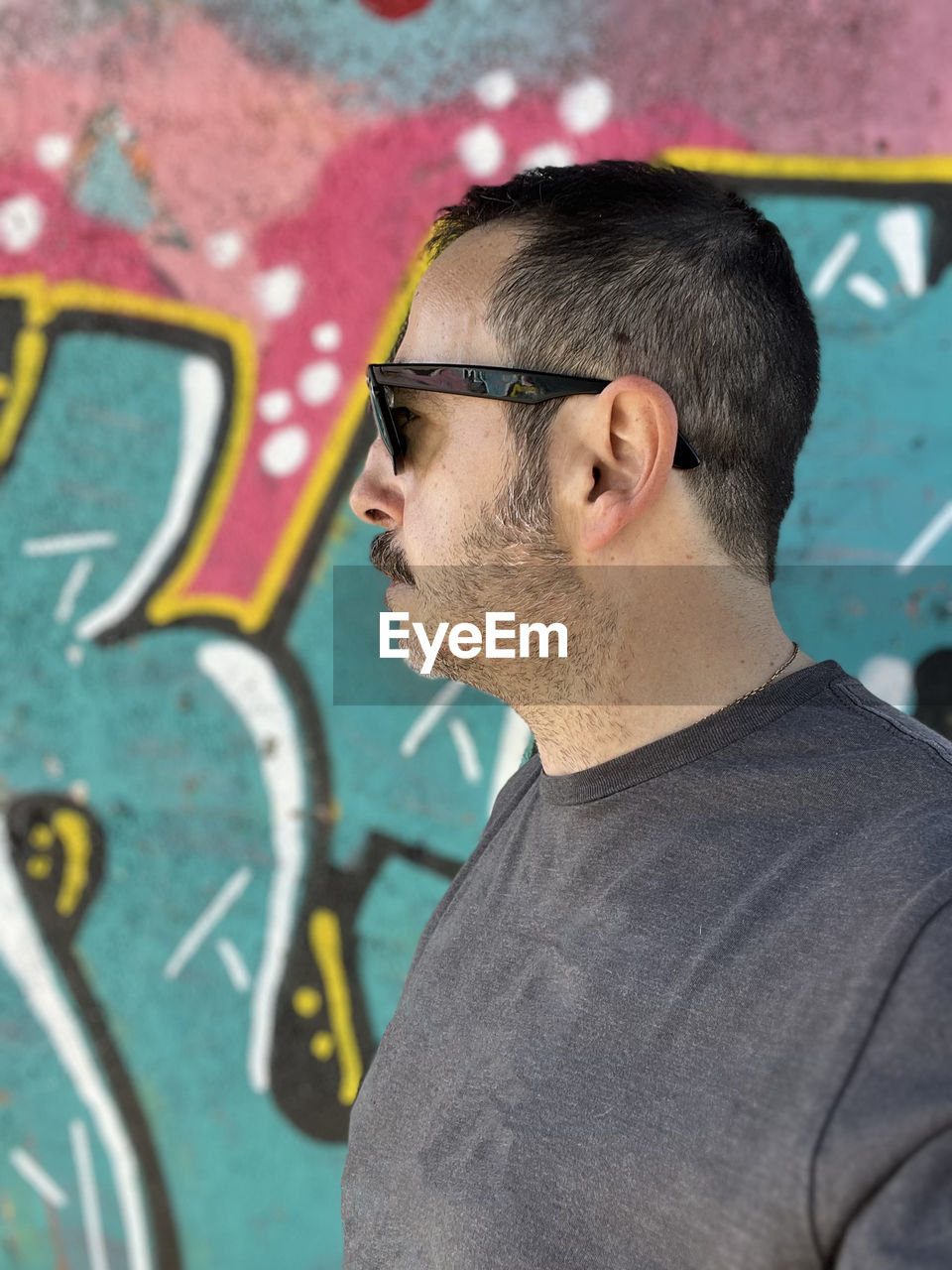 portrait of young man wearing sunglasses standing against wall