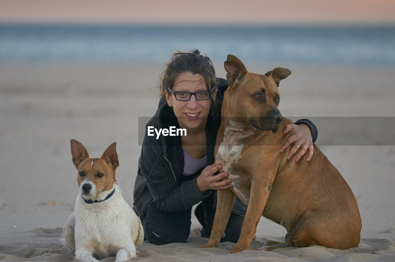 DOGS ON BEACH BY SEA AGAINST SKY