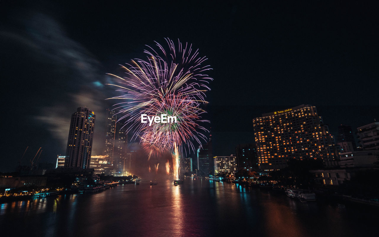 Firework display over illuminated buildings in city at night