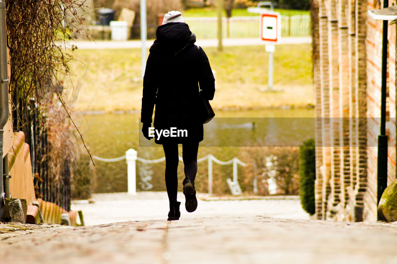 Rear view of woman walking on pathway amidst buildings