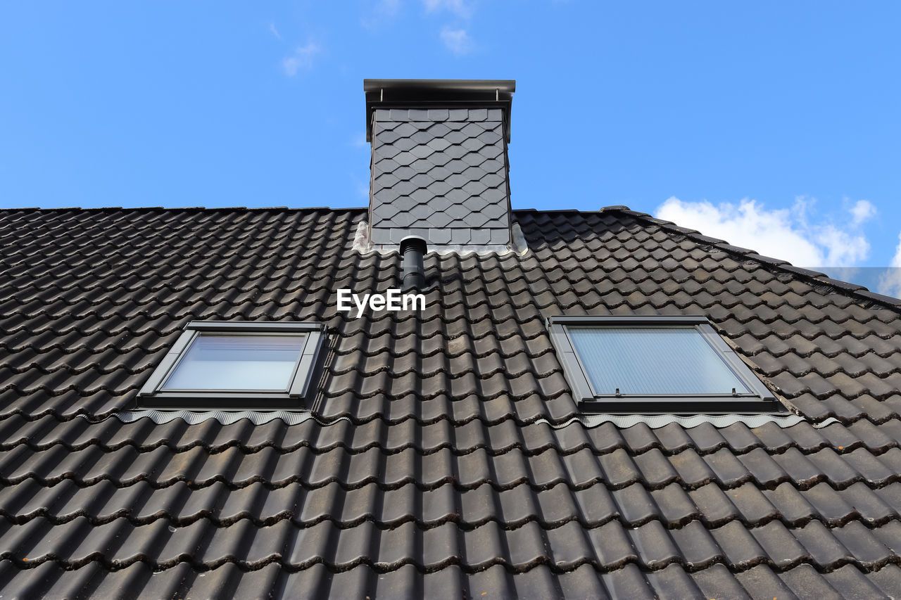 Roof window in velux style with black roof tiles