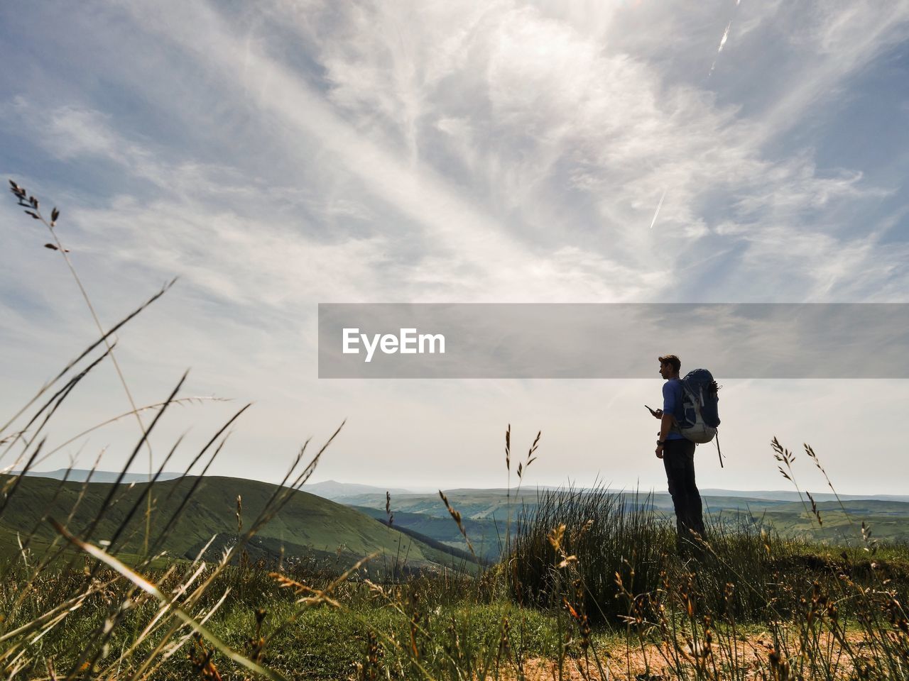 REAR VIEW OF MAN STANDING AGAINST SKY