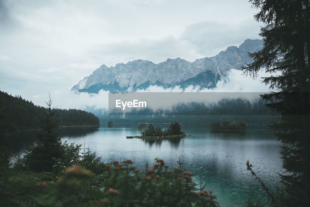 Scenic view of lake and mountains against cloudy sky