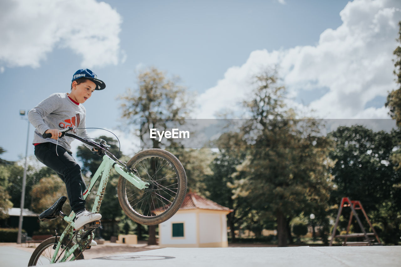 SIDE VIEW OF YOUNG MAN RIDING BICYCLE