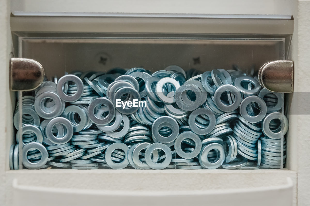 A lot of metal washers in a transparent box. storage of fasteners and parts in a cell