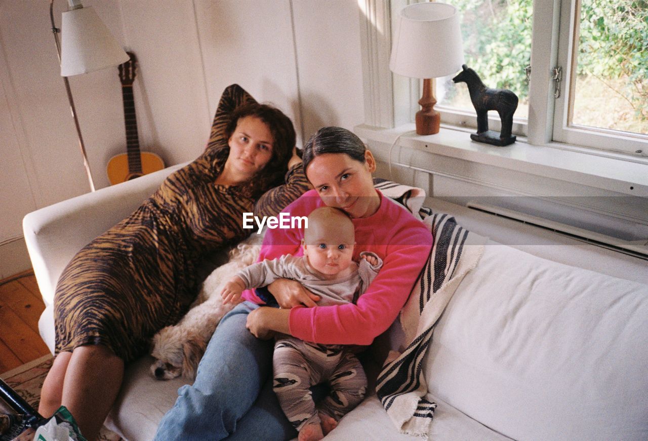 Portrait of smiling family sitting on sofa at home