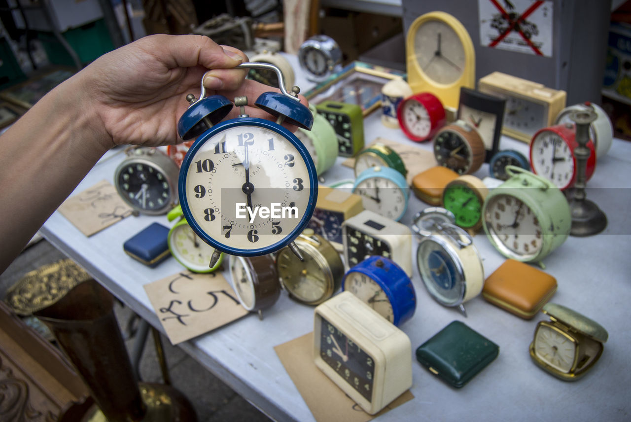 Cropped hand holding alarm clock at market