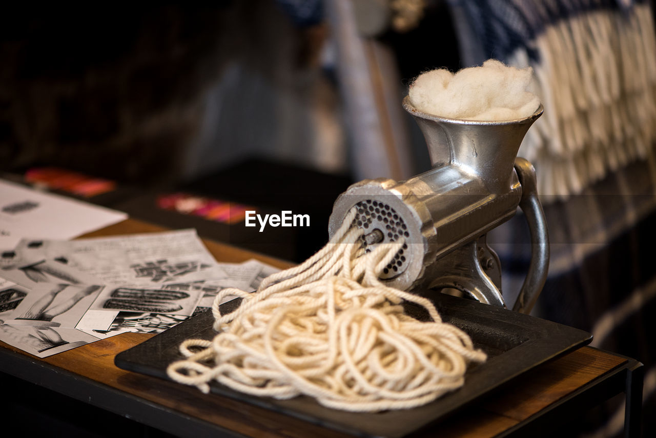 Close-up of pasta coming out from maker on table
