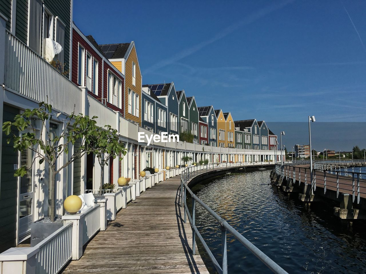 Colorful houses by canal in city against sky