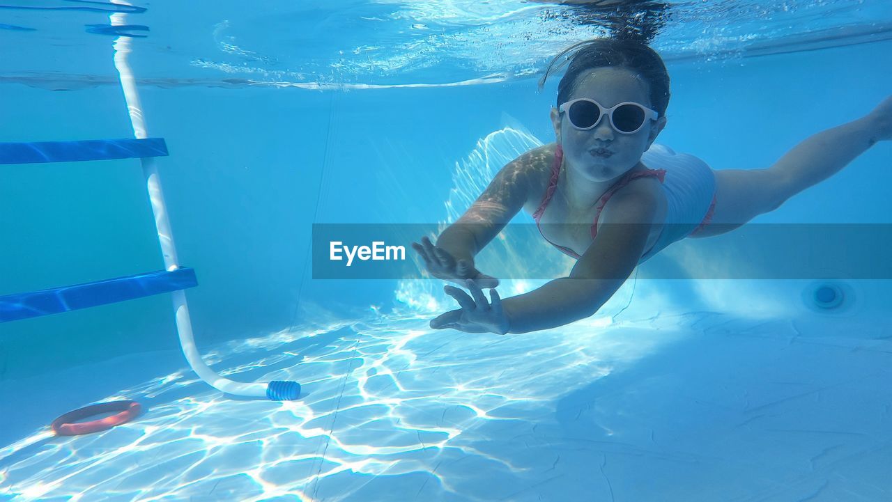 Cool girl with sunglasses is diving in the swimming pool