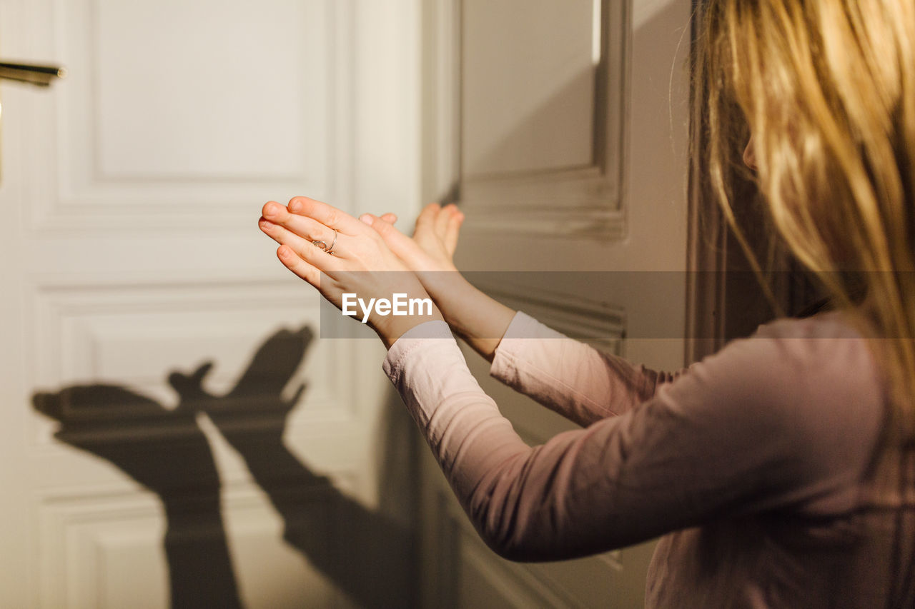 Girl gesturing with shadow on door at home