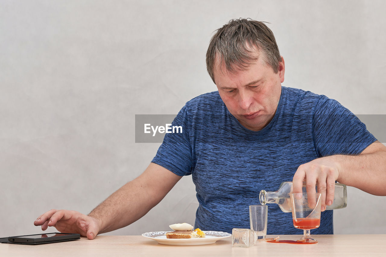 man using mobile phone while sitting on table