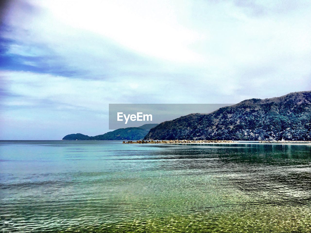 Scenic view of calm sea against cloudy sky