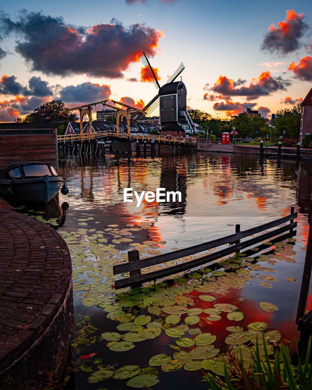 BOATS IN RIVER AGAINST ORANGE SKY