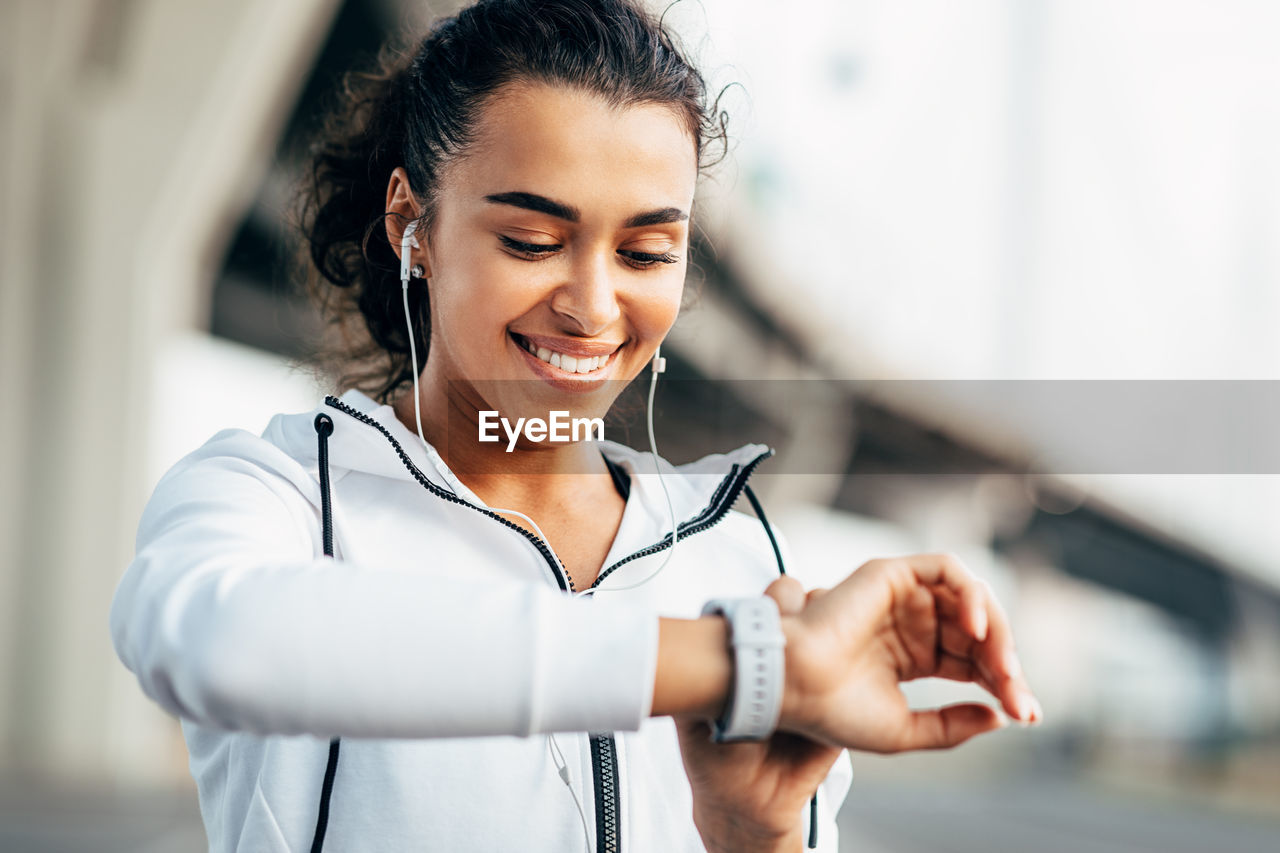 HAPPY YOUNG WOMAN LOOKING AWAY WHILE HOLDING CAMERA