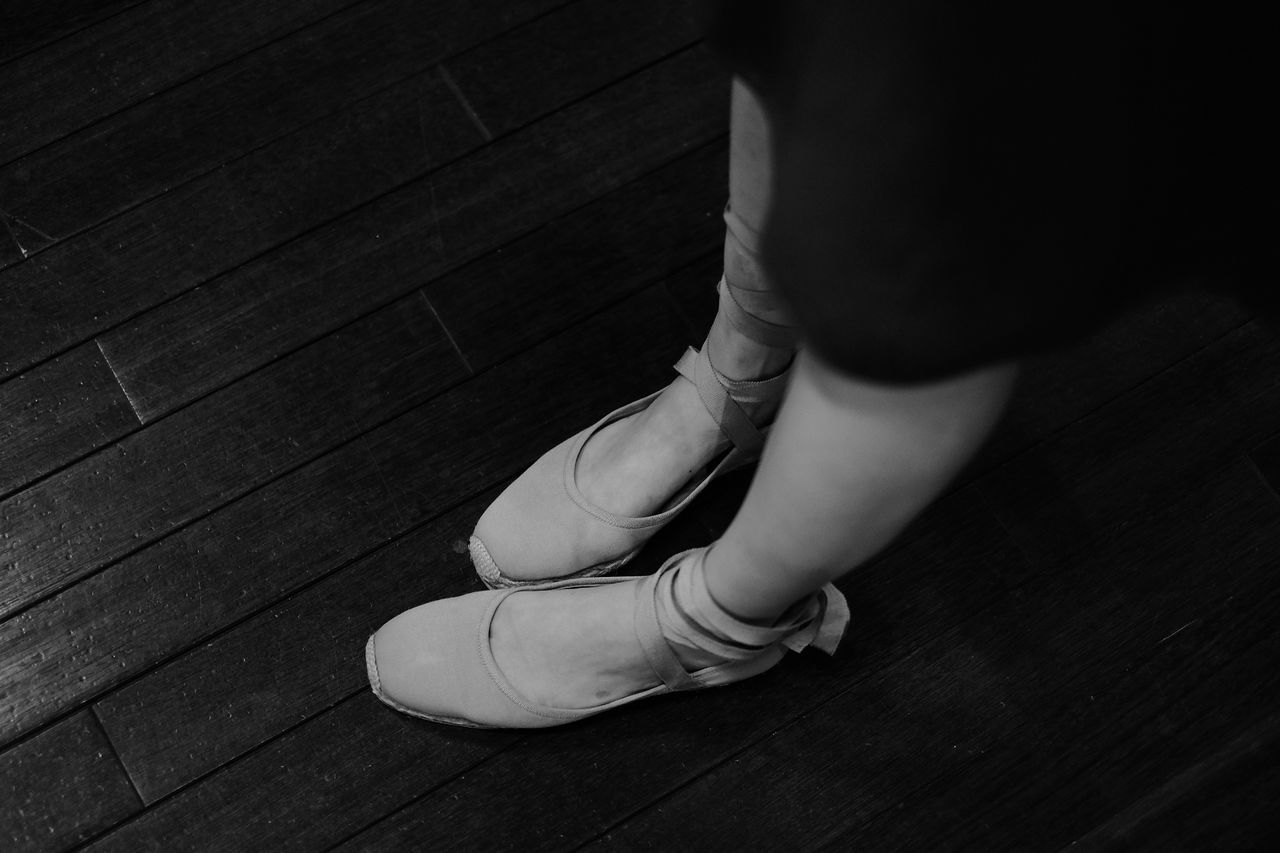 Low section of ballet dancer standing on hardwood floor